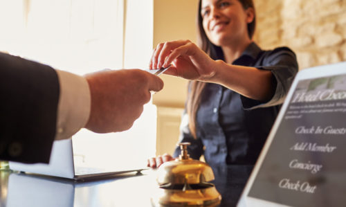 Picture of a hotel receptionists handing a guest their key